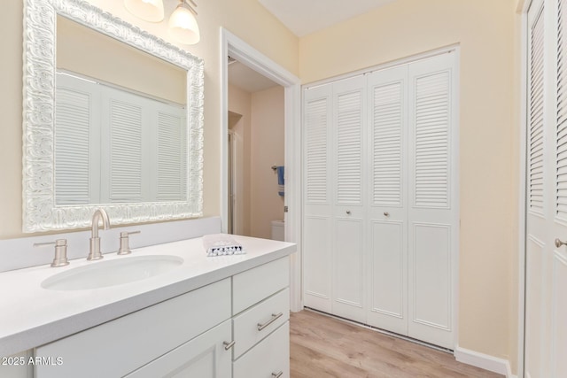 bathroom featuring wood-type flooring, vanity, and toilet