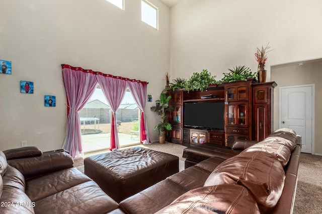 carpeted living room featuring a healthy amount of sunlight and a towering ceiling