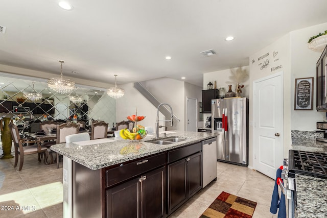 kitchen featuring an island with sink, appliances with stainless steel finishes, a chandelier, sink, and decorative light fixtures