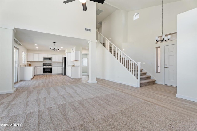 5420 W Grove St, Laveen, AZ 85339 - unfurnished living room featuring a chandelier, stairs, a high ceiling, and light wood-type flooring