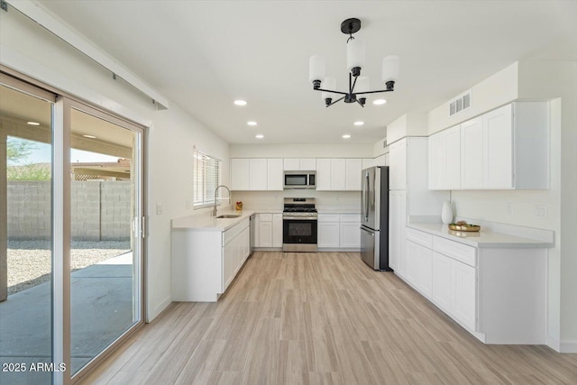 5420 W Grove St, Laveen, AZ 85339 - kitchen featuring appliances with stainless steel finishes, a chandelier, light wood-type flooring, light countertops, and white cabinetry