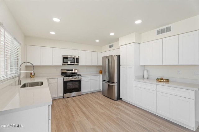 5420 W Grove St, Laveen, AZ 85339 - kitchen with stainless steel appliances, white cabinetry, light countertops, light wood-type flooring, and recessed lighting