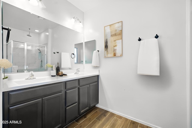 bathroom featuring a sink, double vanity, a shower stall, and wood finished floors
