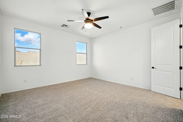 empty room with carpet floors, a ceiling fan, and visible vents