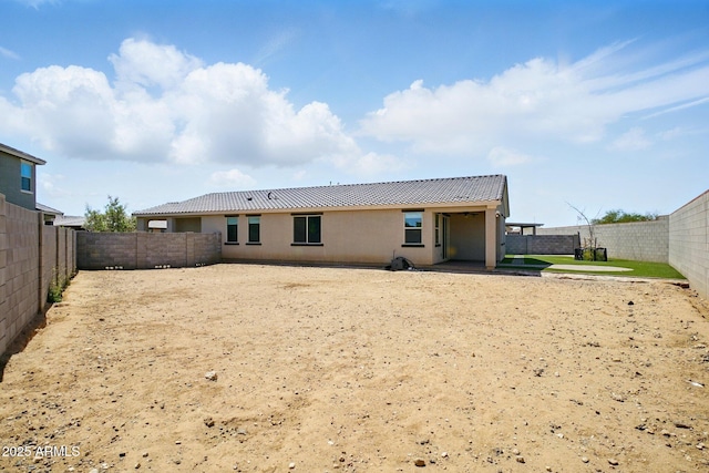 rear view of property with a fenced backyard and stucco siding