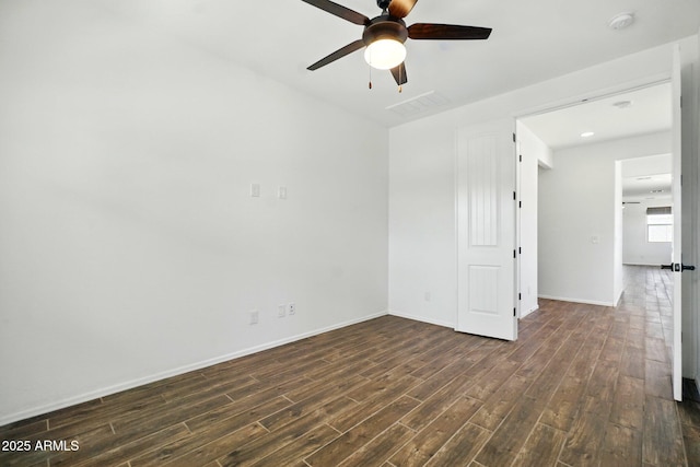 empty room featuring baseboards, a ceiling fan, dark wood-style floors, and visible vents