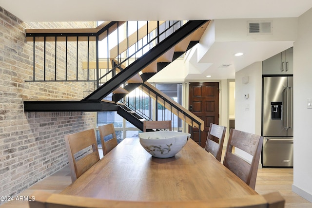 dining space featuring light hardwood / wood-style floors and brick wall