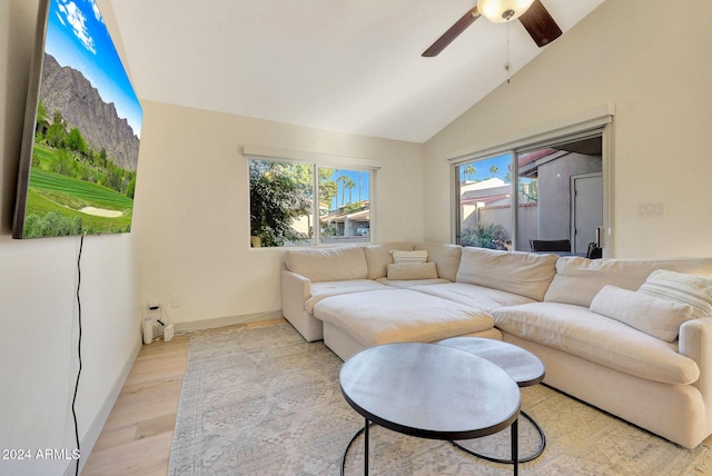 living room featuring ceiling fan, vaulted ceiling, and light hardwood / wood-style flooring