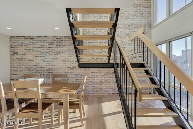 unfurnished dining area featuring wood-type flooring and brick wall