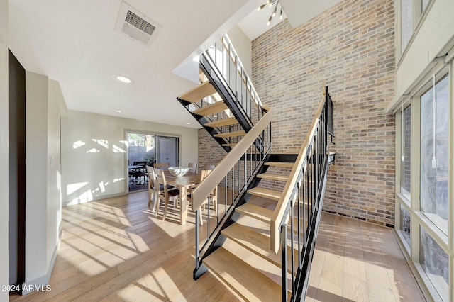 stairs with wood-type flooring and brick wall