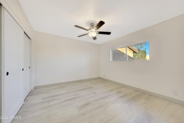 unfurnished bedroom featuring ceiling fan, a closet, and light wood-type flooring