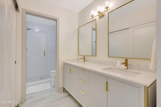 bathroom with hardwood / wood-style flooring, vanity, a shower with shower door, and toilet