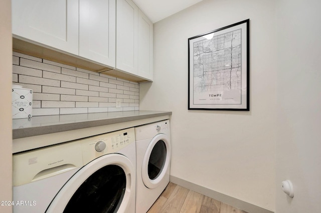 laundry room featuring washer and clothes dryer, light hardwood / wood-style flooring, and cabinets