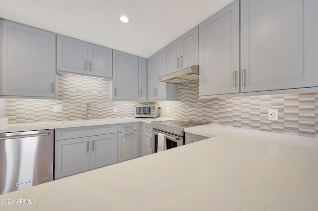 kitchen with tasteful backsplash, gray cabinets, sink, and appliances with stainless steel finishes