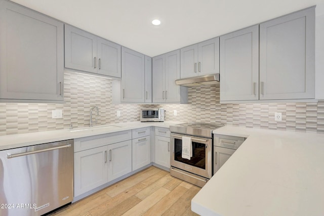 kitchen with decorative backsplash, stainless steel appliances, sink, light hardwood / wood-style flooring, and gray cabinets