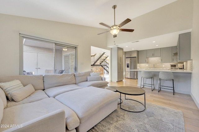 living room with light wood-type flooring, high vaulted ceiling, and ceiling fan