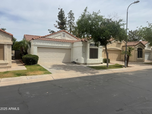 mediterranean / spanish-style home with stucco siding, an attached garage, and a tiled roof