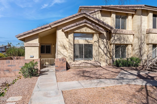 view of front of home with a fenced front yard, a tile roof, and a gate