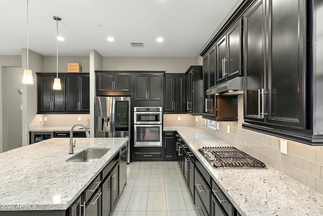 kitchen featuring sink, light stone counters, decorative light fixtures, stainless steel appliances, and decorative backsplash