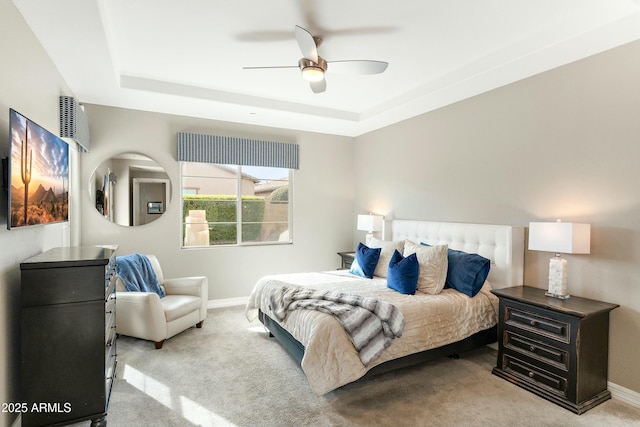 carpeted bedroom featuring ceiling fan and a tray ceiling