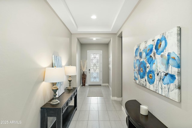 doorway featuring light tile patterned flooring and a tray ceiling