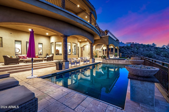 pool at dusk featuring an outdoor living space and a patio