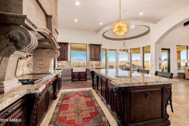 kitchen with light stone countertops, sink, hanging light fixtures, an island with sink, and a breakfast bar area