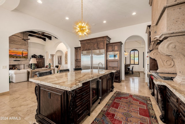 kitchen featuring appliances with stainless steel finishes, a center island with sink, dark brown cabinets, and pendant lighting