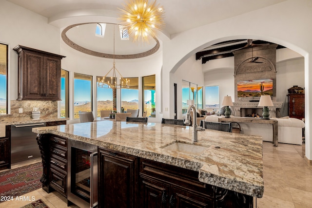 kitchen featuring stainless steel dishwasher, dark brown cabinets, sink, pendant lighting, and an island with sink