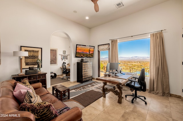 tiled home office featuring ceiling fan and a towering ceiling