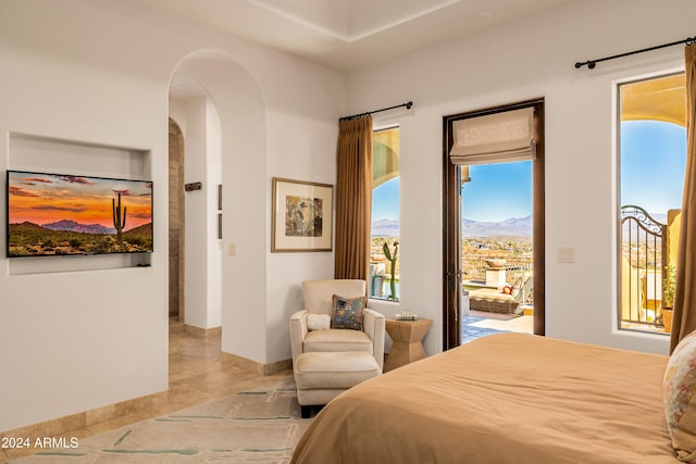 bedroom featuring a mountain view, light tile patterned floors, and access to outside