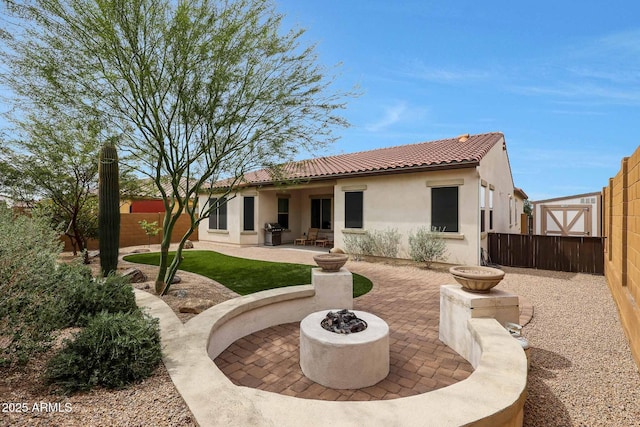 rear view of property with a tile roof, an outdoor fire pit, stucco siding, a fenced backyard, and a patio