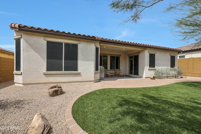 back of property featuring a yard, stucco siding, fence, and a patio