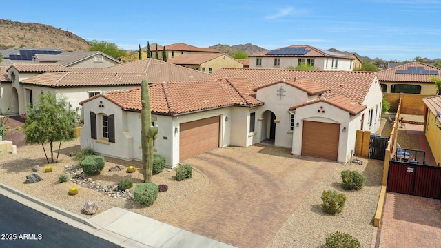 mediterranean / spanish house featuring decorative driveway, a tile roof, stucco siding, and an attached garage
