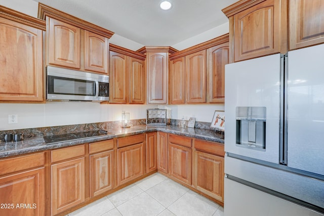 kitchen featuring light tile patterned floors, white refrigerator with ice dispenser, black electric cooktop, and dark stone counters