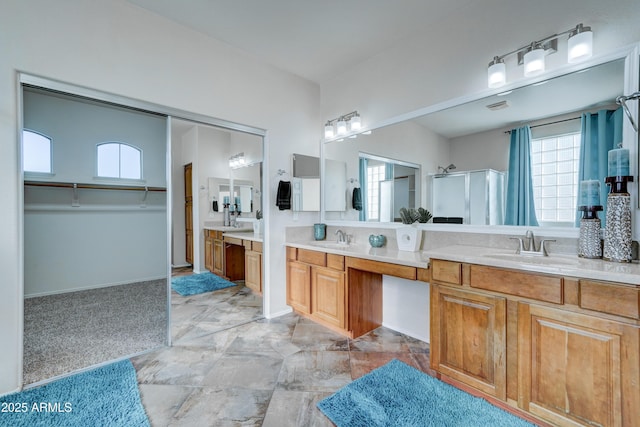 bathroom with a shower with shower door, a healthy amount of sunlight, and vanity