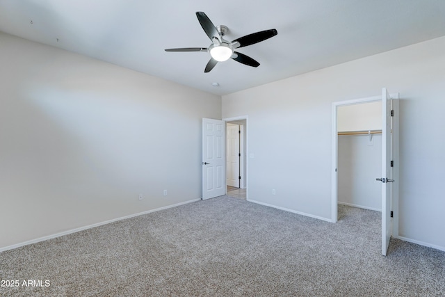 unfurnished bedroom featuring a spacious closet, ceiling fan, carpet, and a closet