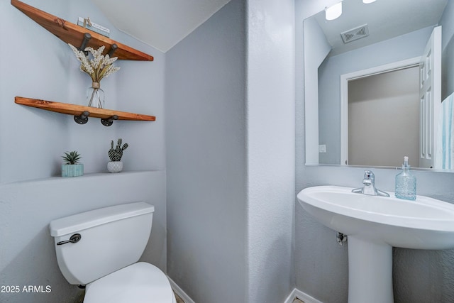 bathroom featuring toilet, vaulted ceiling, and sink