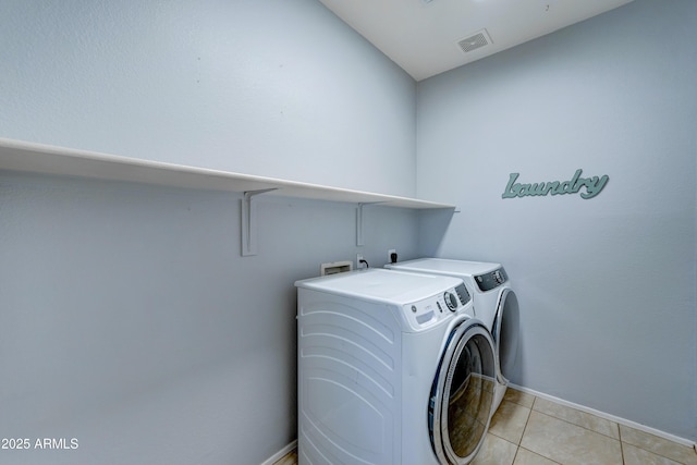 laundry area featuring light tile patterned floors and washer and clothes dryer