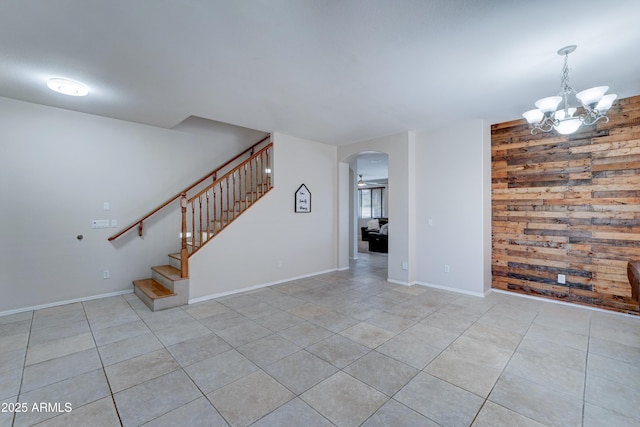 tiled spare room featuring a chandelier and wooden walls