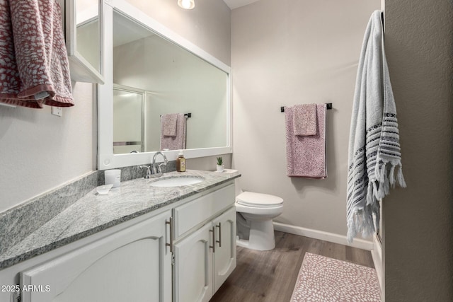 bathroom featuring toilet, vanity, baseboards, and wood finished floors