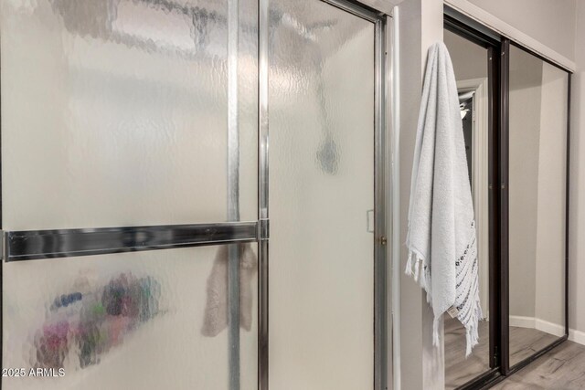 bathroom featuring a stall shower, baseboards, and wood finished floors