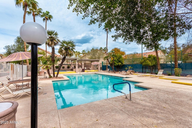 pool with a patio area and fence