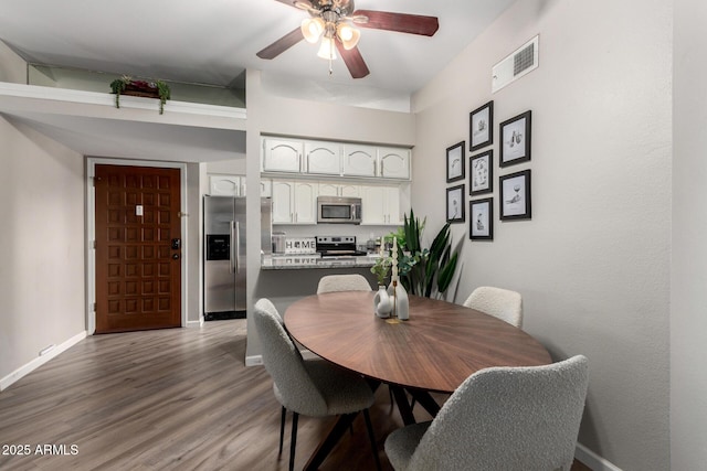 dining area with visible vents, baseboards, a ceiling fan, and wood finished floors