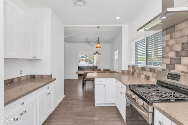 kitchen featuring white cabinets, wood finished floors, wall chimney exhaust hood, tasteful backsplash, and stainless steel range with gas cooktop