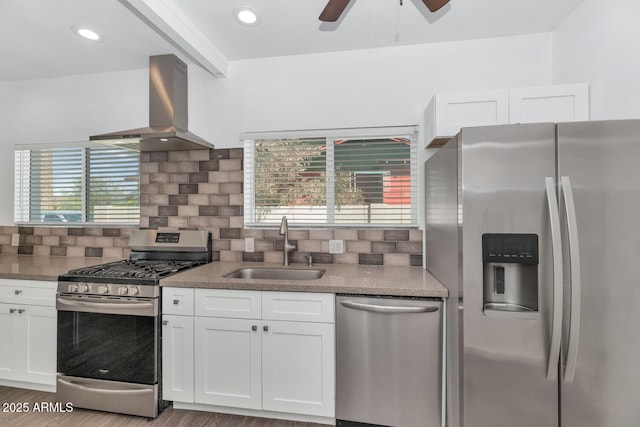 kitchen featuring a sink, wall chimney exhaust hood, appliances with stainless steel finishes, and white cabinets