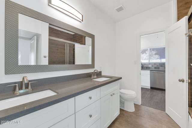 full bathroom with toilet, a sink, a stall shower, and visible vents