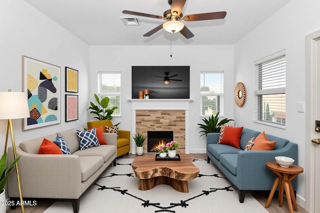 living room featuring a ceiling fan, a tile fireplace, and visible vents