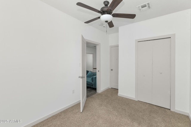 unfurnished bedroom featuring light carpet, baseboards, visible vents, and a closet