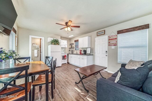 living area featuring baseboards, ceiling fan, and wood finished floors